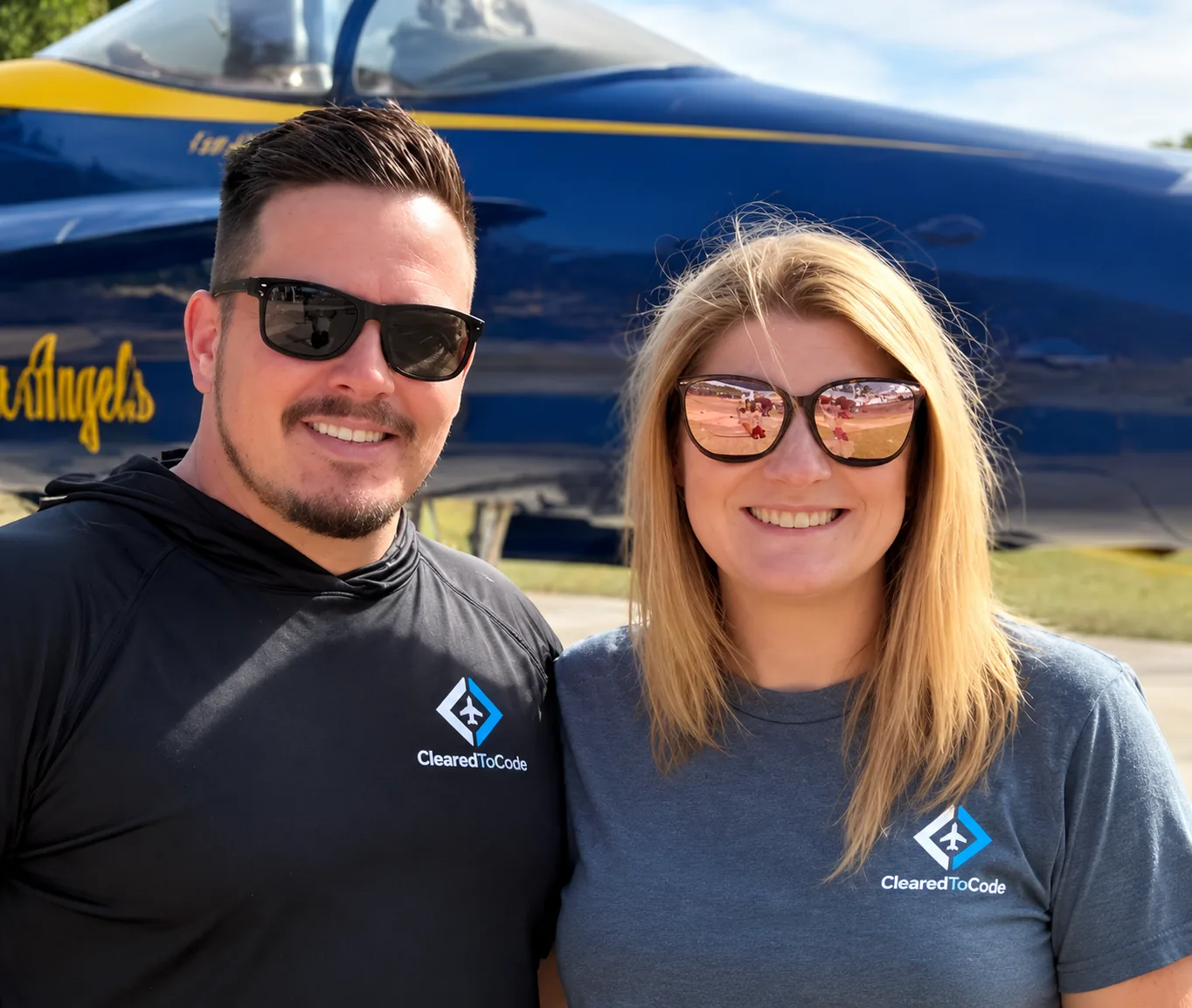 Jesse and Meggan Manchester in ClearedToCode shirts in front of a Blue Angels jet